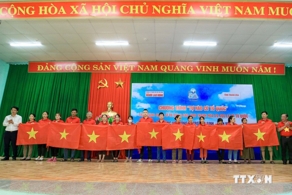 Đại diện lãnh đạo tỉnh Thanh Hóa và báo Người lao động tặng cờ tổ quốc cho người dân. Ảnh: Trịnh Duy Hưng - TTXVN