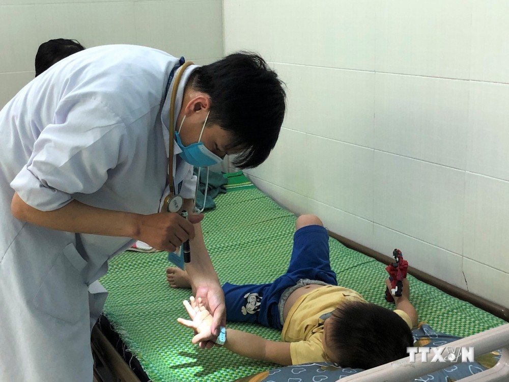 Bác sĩ kiểm tra sức khỏe cho trẻ mắc tay chân miệng tại Khoa Bệnh Nhiệt đới, Bệnh viện Sản Nhi Quảng Ngãi, tỉnh Quảng Ngãi. Ảnh: Đinh Hương - TTXVN