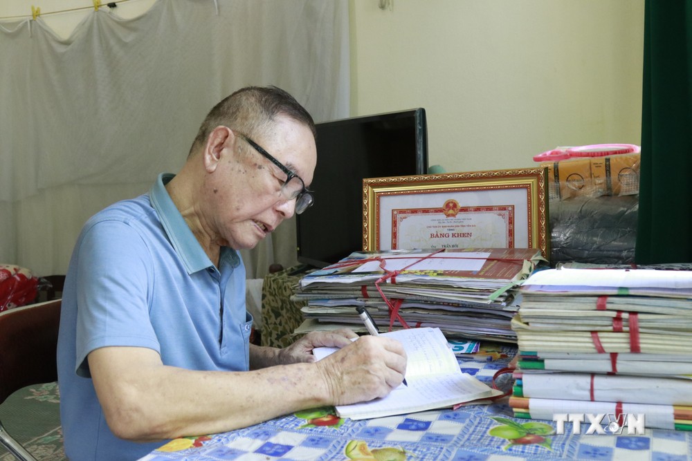 Dù năm nay đã hơn 80 tuổi, nhưng ông Trần Đức Hồi vẫn ngày ngày ghi chép lại từng trang viết, bài báo hay mà ông sưu tầm được về Bác Hồ. Ảnh: Tuấn Anh - TTXVN