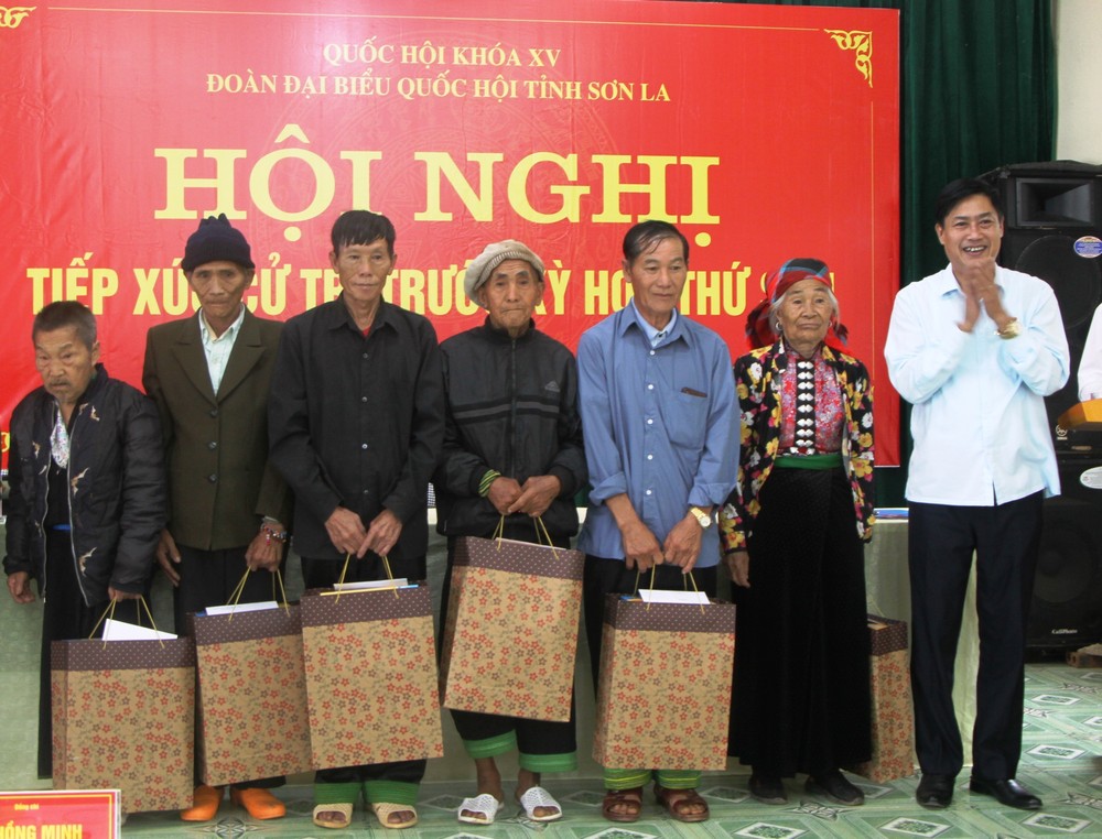 Bí thư Tỉnh ủy, Trưởng đoàn Đại biểu Quốc hội tỉnh Sơn La Nguyễn Hữu Đông (ngoài cùng bên phải) trao quà cho các hộ gia đình có công với cách mạng trên địa bàn huyện Mường La. Ảnh: Phan Quân - TTXVN