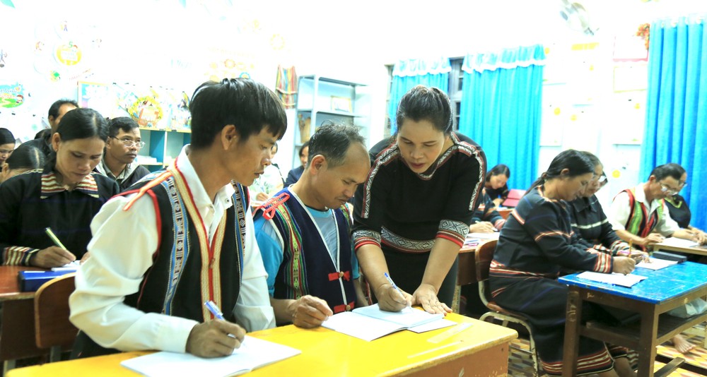 Cô giáo Kso H'Vớt đang chăm chú uốn nắn từng nét chữ cho các học viên. Ảnh: Quang Thái- TTXVN