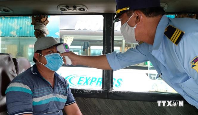 Lực lượng chức năng bến xe phía Bắc thành phố Nha Trang kiểm tra thân nhiệt hành khách khi lên xe. Ảnh: Nguyễn Dũng – TTXVN