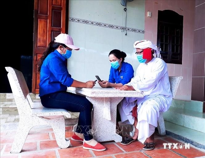 Đoàn viên, thanh niên Ninh Thuận hướng dẫn người dân cài đặt ứng dụng Bluezone trên điện thoại thông minh. Ảnh: Công Thử - TTXVN