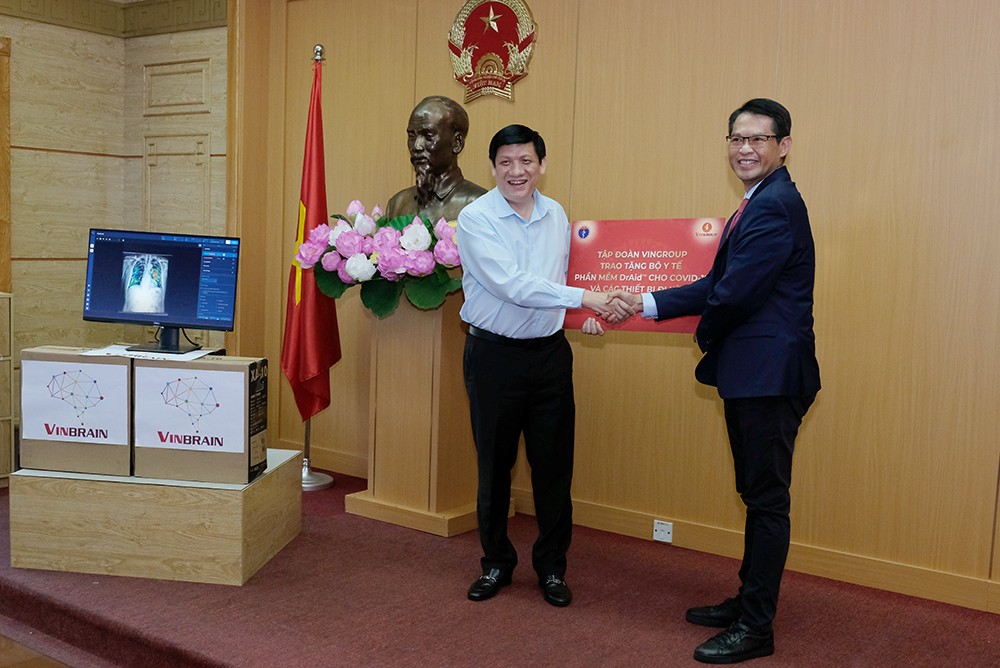 Quyền Bộ trưởng Bộ Y tế Nguyễn Thanh Long nhận biểu trưng phần mềm DrAid™ cùng các thiết bị đi kèm để hỗ trợ đánh giá tiên lượng trong điều trị COVID-19 từ ông Trương Quốc Hùng, Tổng giám đốc VinBrain. ncov.moh.gov.vn
