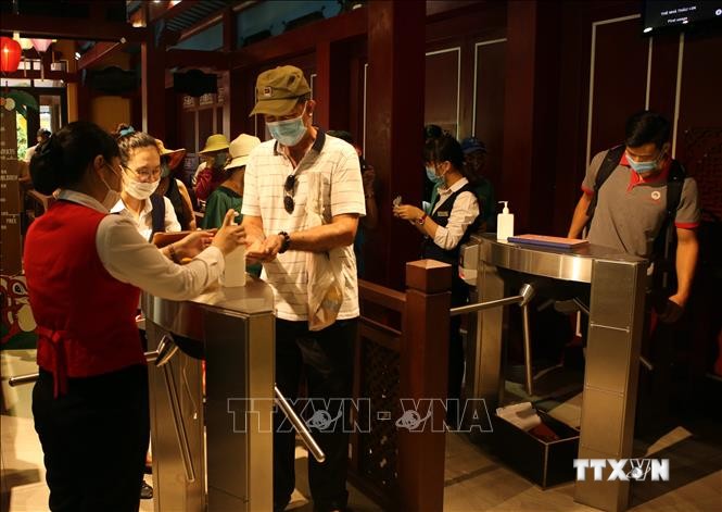 Du khách thực hiện sát khuẩn tay khi vào cửa soát vé để thăm quan Khu du lịch Bà Nà Hills. Ảnh: Trần Lê Lâm - TTXVN