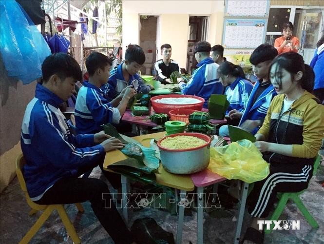Các em Trường THPT Nguyễn Cảnh Chân, huyện Thanh Chương (Nghệ An) gói bánh chưng ủng hộ đồng bào bị ảnh hưởng bởi lũ lụt. Ảnh: TTXVN phát