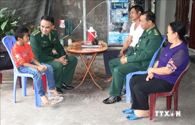 Thượng tá Vũ Hải Ninh, Đồn Biên phòng Kim Sơn (áo xanh, bên trái) hiện là "cha nuôi" của em Lê Nguyễn Công Huy ở khối 6, thị trấn Bình Minh, huyện Kim Sơn, tỉnh Ninh Bình. Ảnh: Thùy Dung - TTXVN  