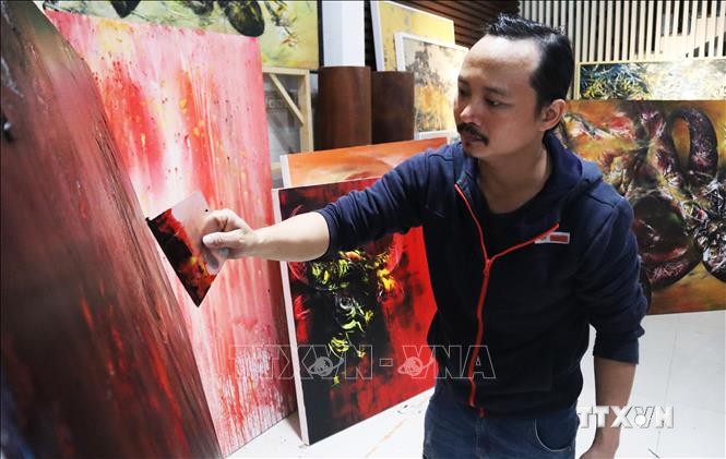 Họa sĩ Ngô Thanh Hùng sáng tác tranh tại nhà. Ảnh: Văn Dũng - TTXVN