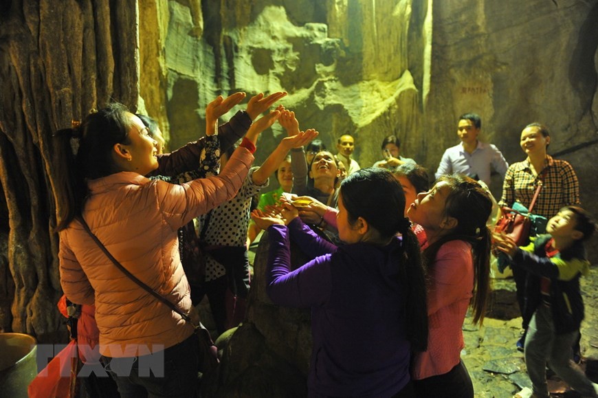 Các du khách đón những giọt nước từ nhũ đá trong động Hương Tích để cầu mong một năm mới nhiều sức khỏe, an lành và hạnh phúc. Ảnh: Minh Đức - TTXVN