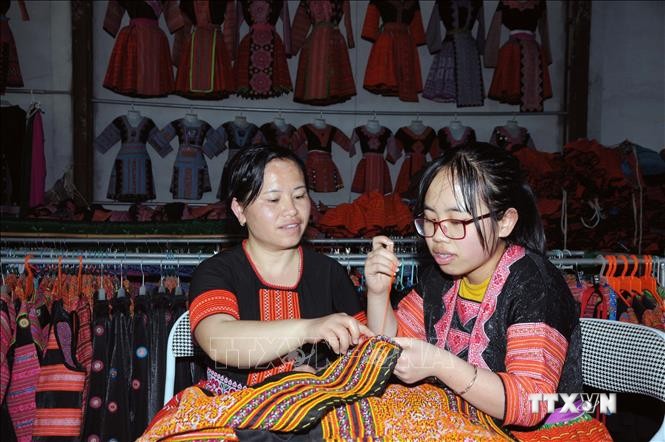 Chị Tráng Thị Dua (bên trái) truyền dạy nghề thêu, may truyền thống của đồng bào dân tộc Mông cho con gái. Ảnh: Quang Quyết-TTXVN