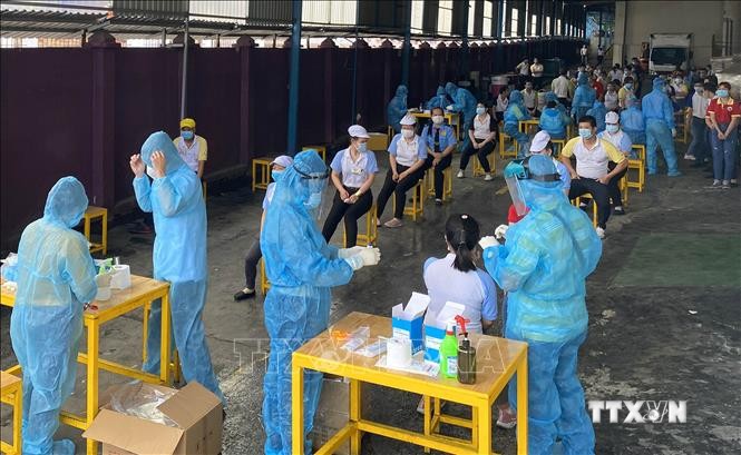 Các y bác sĩ Trung tâm kiểm soát bệnh tật Thành phố Hồ Chí Minh thực hiện xét nghiệm sàng lọc COVID-19 ngẫu nhiên cho công nhân. Ảnh: Thanh Vũ - TTXVN