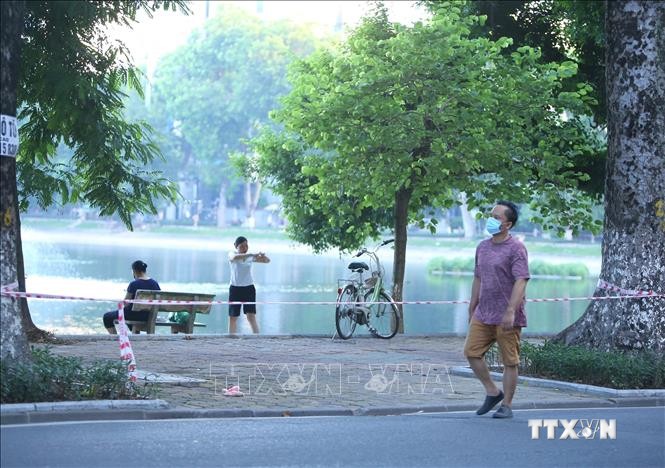 Nhiều người dân vẫn tập thể dục tại khu vực hồ Thiền Quang (Hà Nội) dù đã được lực lượng chức năng căng dây, cắm biển cấm . Ảnh: Hoàng Hiếu - TTXVN
