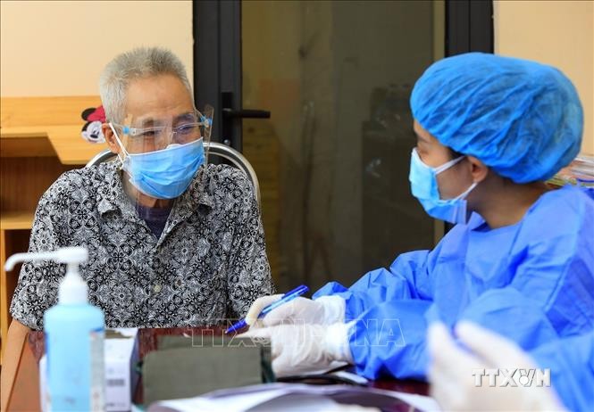 Ông Trịnh Xuân Nghĩa (77 tuổi), phường Trung Hòa, quận Cầu Giấy được nhân viên y tế tư vấn trước khi tiêm vaccine phòng COVID-19 . Ảnh: Tuấn Anh - TTXVN