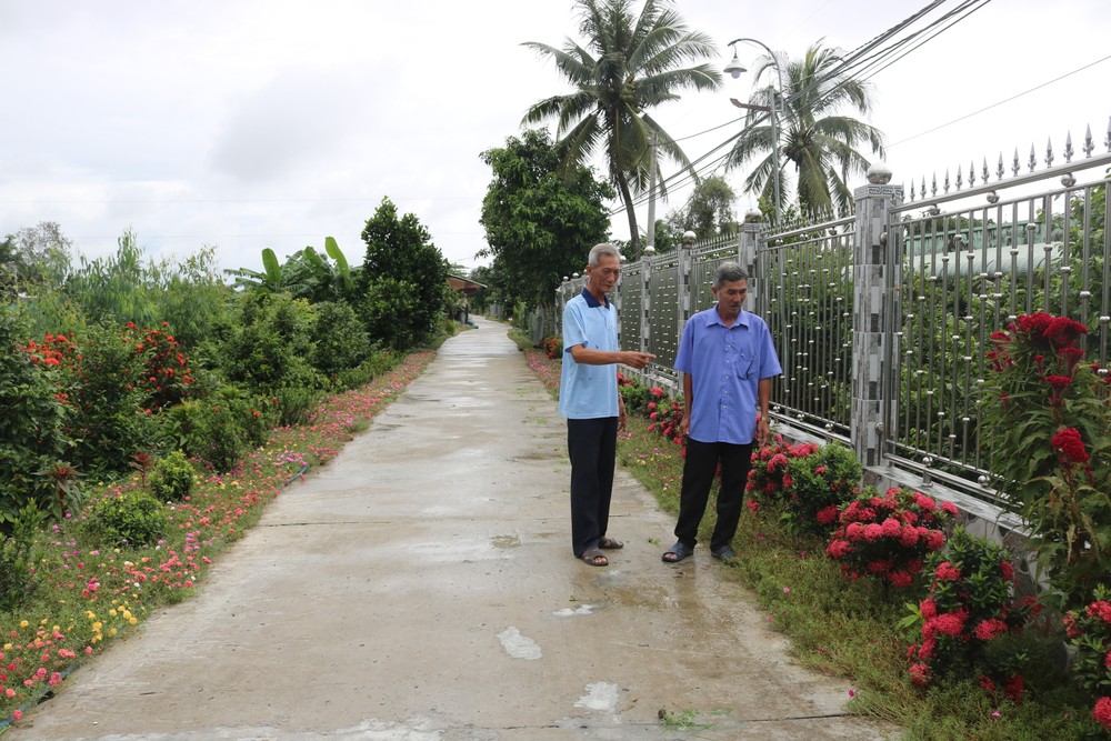Người dân trao đổi với cán bộ về trồng hàng rào hoa để tạo cảnh quan sạch đẹp cho đường làng, ngõ xóm. Ảnh: cailay.tiengiang.gov.vn
