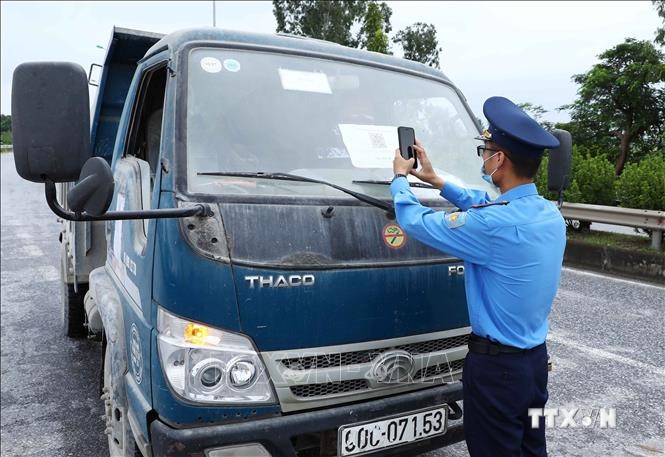 Lực lượng chức năng quét mã QR của phương tiện tham gia giao thông tại chốt kiểm soát dịch ngã 3 Cầu Giẽ, huyện Phú Xuyên hướng từ Hà Nam về Hà Nội trên tuyến Quốc lộ 1A. Ảnh: Phạm Kiên - TTXVN  
