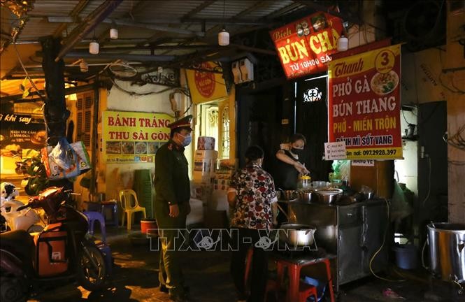 Lực lượng chức năng phường Hàng Bồ (quận Hoàn Kiếm) nhắc nhở các hộ kinh doanh ăn uống đóng cửa đúng 21 giờ. Ảnh: Hoàng Hiếu - TTXVN
