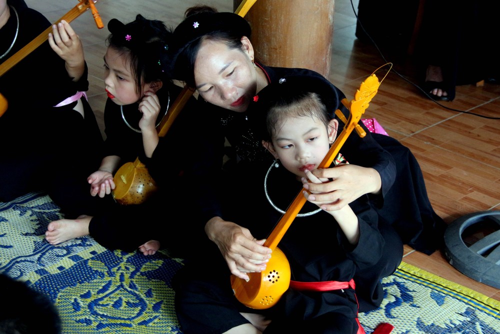 Chị Đàm Thanh Hiền hướng dẫn các cháu nhỏ cách chơi đàn Tính. Ảnh: Quang Cường - TTXVN
