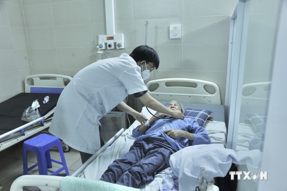 Bác sỹ thăm khám sức khỏe bệnh nhân COVID-19 tại Bệnh viện Thanh Nhàn. Ảnh: TTXVN phát

