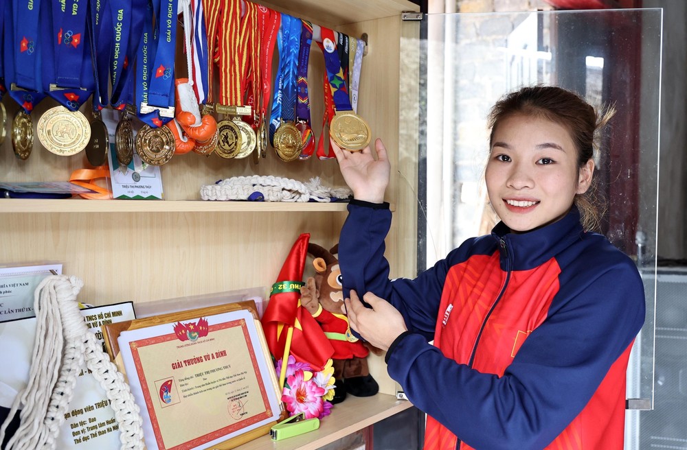Vận động viên Triệu Thị Phương Thủy bên tủ huy chương các loại mà cô đã giành được. Ảnh: Trung Kiên - TTXVN