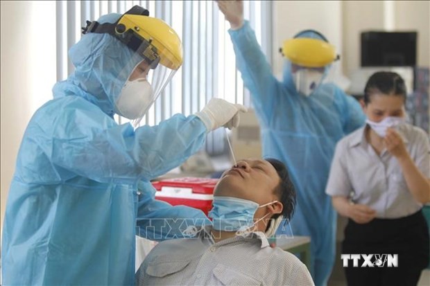 Các y bác sỹ Trung tâm y tế Quận 7 thực hiện xét nghiệm sàng lọc COVID-19 ngẫu nhiên cho công nhân tại Công ty TNHH Kim may Organ Việt Nam. Ảnh: Thanh Vũ - TTXVN