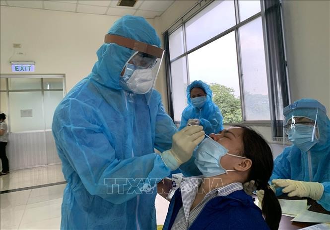 Các y bác sỹ Trung tâm kiểm soát bệnh tật Tp. Hồ Chí Minh và Quận 7 thực hiện xét nghiệm sàng lọc COVID-19 ngẫu nhiên cho công nhân ngày 3/6. Ảnh: Thanh Vũ - TTXVN